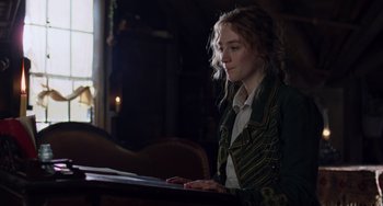Movie still from “Little Women” (2019), directed by Greta Gerwig – A woman sitting at a table looking at a book; Medium shot, Low angle