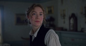 Movie still from “Little Women” (2019), directed by Greta Gerwig – A young woman in a white shirt and black vest; Close Up shot, Low angle