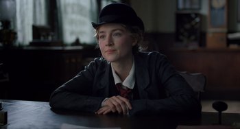 Movie still from “Little Women” (2019), directed by Greta Gerwig – A woman sitting at a table wearing a black hat; Close Up shot, Over the shoulder angle