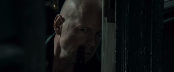 Movie still from “Live Free or Die Hard” (2007), directed by Len Wiseman – A man with a shaved bald head looking at the camera; Close Up shot, Over the shoulder angle