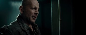 Movie still from “Live Free or Die Hard” (2007), directed by Len Wiseman – A bald man with a goatee is standing in front of a mirror; Close Up shot, Over the shoulder angle