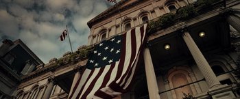 Movie still from “Live Free or Die Hard” (2007), directed by Len Wiseman – An american flag hanging in front of a building; Extreme Wide shot, Low angle