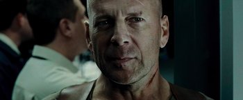 Movie still from “Live Free or Die Hard” (2007), directed by Len Wiseman – A man with a shaved head and a scar on his face; Close Up shot, Over the shoulder angle