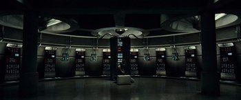 Movie still from “Live Free or Die Hard” (2007), directed by Len Wiseman – A man standing on a bench in front of a bunch of guns; Extreme Wide shot, High angle