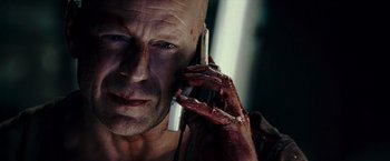 Movie still from “Live Free or Die Hard” (2007), directed by Len Wiseman – A man with blood all over his face is talking on a cell phone; Close Up shot, Overhead angle