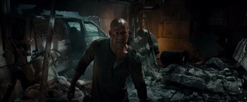 Movie still from “Live Free or Die Hard” (2007), directed by Len Wiseman – A bald man in a room with rubble and a car; Medium shot, Low angle