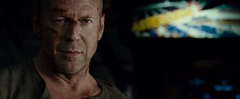 Movie still from “Live Free or Die Hard” (2007), directed by Len Wiseman – A man with a shaved head is looking at the camera; Close Up shot, Low angle