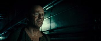 Movie still from “Live Free or Die Hard” (2007), directed by Len Wiseman – A bald man in a green shirt is looking at the camera; Close Up shot, Low angle