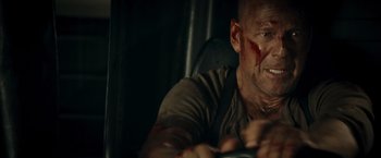 Movie still from “Live Free or Die Hard” (2007), directed by Len Wiseman – A man with blood all over his face is driving a car; Close Up shot, Low angle