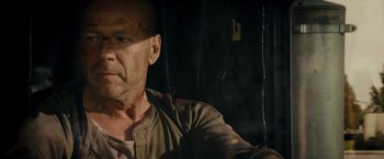 Movie still from “Live Free or Die Hard” (2007), directed by Len Wiseman – A bald man in a brown shirt is looking at the camera; Close Up shot, Over the shoulder angle