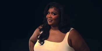 Movie still from “Lizzo: Live in Concert” (2022), directed by Brad Duns – A woman in a white top posing for a picture; Close Up shot, Low angle
