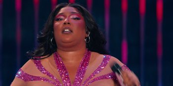 Movie still from “Lizzo: Live in Concert” (2022), directed by Brad Duns – A woman in a pink dress holding a microphone in her hand; Close Up shot, Low angle