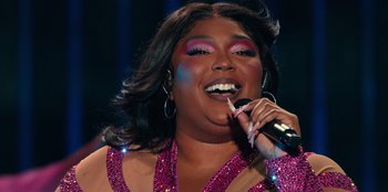 Movie still from “Lizzo: Live in Concert” (2022), directed by Brad Duns – A woman is singing into a microphone while wearing pink makeup; Close Up shot, Low angle