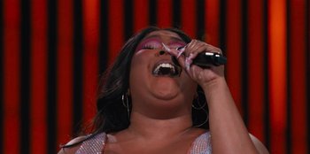 Movie still from “Lizzo: Live in Concert” (2022), directed by Brad Duns – A woman singing into a microphone on a stage; Extreme Close Up shot, Low angle