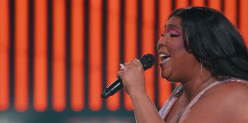 Movie still from “Lizzo: Live in Concert” (2022), directed by Brad Duns – A woman is holding a microphone and singing; Medium shot, Low angle