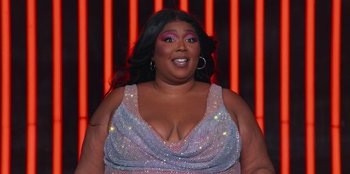 Movie still from “Lizzo: Live in Concert” (2022), directed by Brad Duns – A woman in a silver dress and big black hair; Close Up shot, Low angle