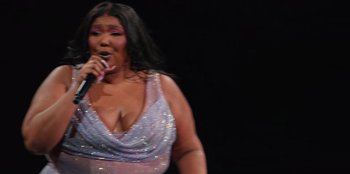 Movie still from “Lizzo: Live in Concert” (2022), directed by Brad Duns – A woman in a purple dress is singing; Medium shot, Low angle