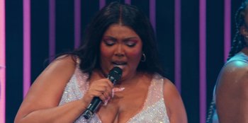 Movie still from “Lizzo: Live in Concert” (2022), directed by Brad Duns – A woman in a white dress holding a microphone up to her mouth; Close Up shot, High angle