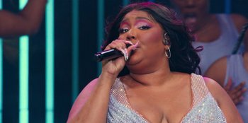 Movie still from “Lizzo: Live in Concert” (2022), directed by Brad Duns – A woman in a silver dress singing into a microphone; Close Up shot, Low angle