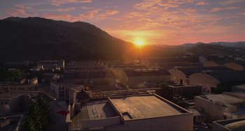 Movie still from “Locked Down” (2021), directed by Doug Liman – The sun sets over a city with a mountain in the background; Extreme Wide shot, High angle