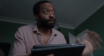 Movie still from “Locked Down” (2021), directed by Doug Liman – A man with a surprised look on his face looking at a computer; Close Up shot, Low angle