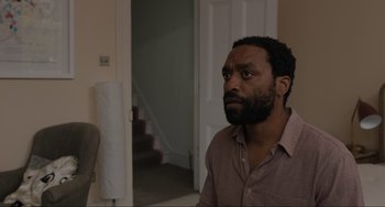 Movie still from “Locked Down” (2021), directed by Doug Liman – A man standing in front of a door looking up; Medium shot, Over the shoulder angle