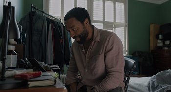 Movie still from “Locked Down” (2021), directed by Doug Liman – A man sitting at a table in front of a window; Medium shot, Over the shoulder angle