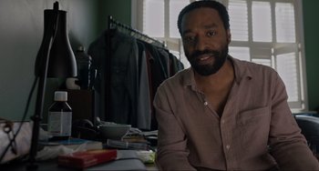 Movie still from “Locked Down” (2021), directed by Doug Liman – A man sitting at a table in front of a window; Close Up shot, Low angle