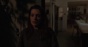 Movie still from “Locked Down” (2021), directed by Doug Liman – A woman standing in a dark room with her head turned to the side; Medium shot, Over the shoulder angle