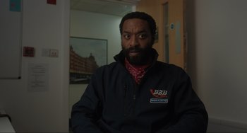 Movie still from “Locked Down” (2021), directed by Doug Liman – A man with a beard wearing a black jacket; Medium shot, Over the shoulder angle