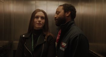 Movie still from “Locked Down” (2021), directed by Doug Liman – A man and a woman standing next to each other in an elevator; Close Up shot, Over the shoulder angle
