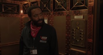 Movie still from “Locked Down” (2021), directed by Doug Liman – A man with a beard wearing a red bandanna; Medium shot, Over the shoulder angle