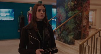 Movie still from “Locked Down” (2021), directed by Doug Liman – A woman in a black jacket holding a wallet; Medium shot, Over the shoulder angle