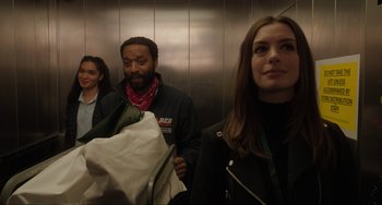 Movie still from “Locked Down” (2021), directed by Doug Liman – Three people in an elevator , one of whom is holding a blanket; Medium shot, Over the shoulder angle