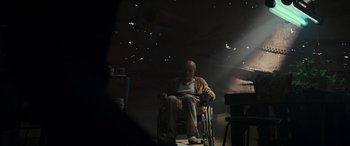 Movie still from “Logan” (2017), directed by James Mangold – An old man sitting in a wheel chair in a dark room; Wide shot, Low angle