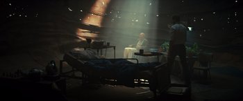 Movie still from “Logan” (2017), directed by James Mangold – A man sitting on a chair in a room; Wide shot, High angle