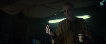 Movie still from “Logan” (2017), directed by James Mangold – A bald man holding a cell phone in his hand; Medium shot, Low angle