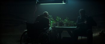 Movie still from “Logan” (2017), directed by James Mangold – An old man sitting in a wheel chair next to potted plants; Wide shot, Low angle
