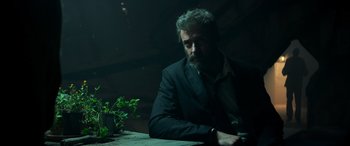 Movie still from “Logan” (2017), directed by James Mangold – A man sitting at a table in a dark room; Close Up shot, Low angle