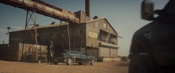 Movie still from “Logan” (2017), directed by James Mangold – A man standing next to a car in front of a building; Wide shot, Low angle