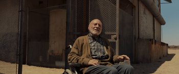 Movie still from “Logan” (2017), directed by James Mangold – An older man sitting in a chair outside; Medium shot, Low angle
