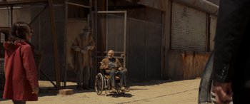 Movie still from “Logan” (2017), directed by James Mangold – An old man sitting in a wheel chair in front of a fence; Wide shot, Low angle