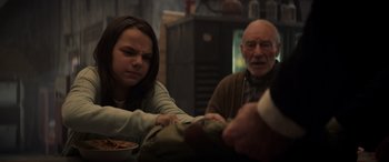 Movie still from “Logan” (2017), directed by James Mangold – An older man and a younger woman sitting at a table; Medium shot, Over the shoulder angle