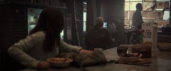 Movie still from “Logan” (2017), directed by James Mangold – Two people sitting at a table watching television; Wide shot, Over the shoulder angle