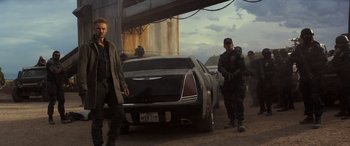 Movie still from “Logan” (2017), directed by James Mangold – A group of men standing next to a car; Wide shot, Low angle