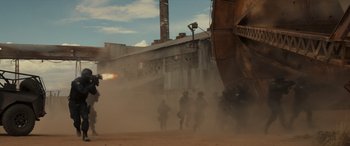 Movie still from “Logan” (2017), directed by James Mangold – A group of people standing in the dirt near a building; Extreme Wide shot, Low angle