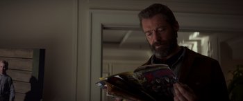 Movie still from “Logan” (2017), directed by James Mangold – A man reading a comic book while standing in front of a mirror; Close Up shot, Over the shoulder angle