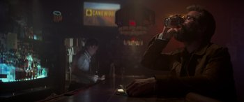 Movie still from “Logan” (2017), directed by James Mangold – A man sitting at a bar taking a picture with a camera; Medium shot, Low angle