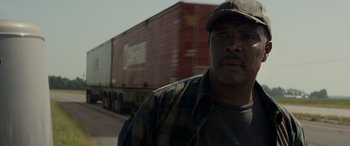 Movie still from “Logan” (2017), directed by James Mangold – A man standing in front of a train on the side of the road; Close Up shot, Low angle