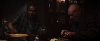Movie still from “Logan” (2017), directed by James Mangold – Two men sitting at a dinner table eating food; Medium shot, Over the shoulder angle